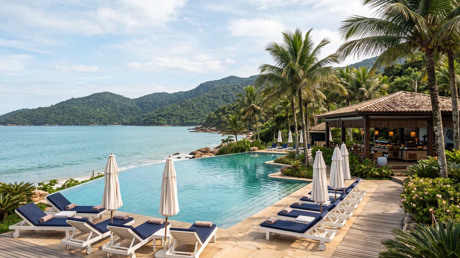 A piscina de um resort com espreguiçadeiras e o mar azul-turquesa atrás.