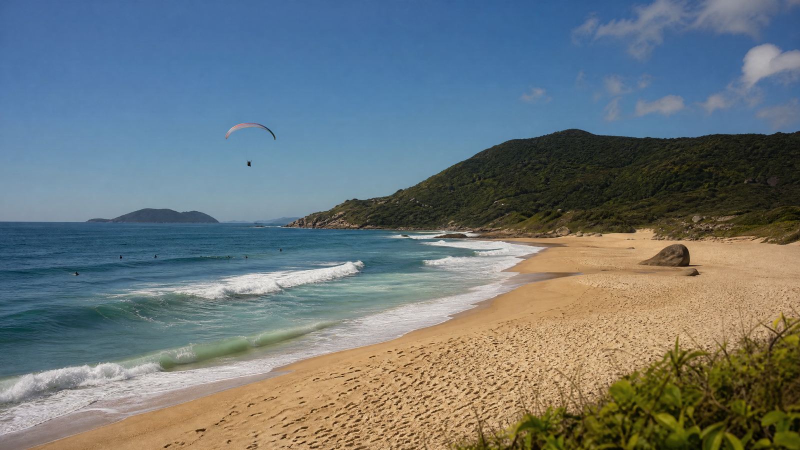 A Praia Mole com surfistas e um parapente no céu.